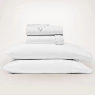 Signature Hemmed Sheet Set in white featuring two stacked pillows and folded sheets.