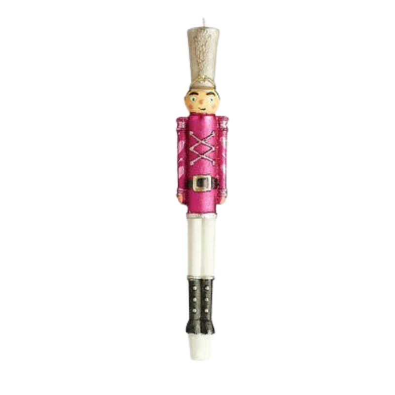 Pink nutcracker soldier taper candle with a gold hat, white pants, and black boots.