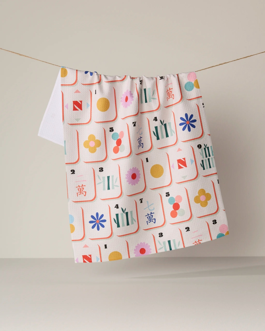 Everyday Tea Towel hanging on a line, featuring a colorful mahjong tile pattern on white fabric.