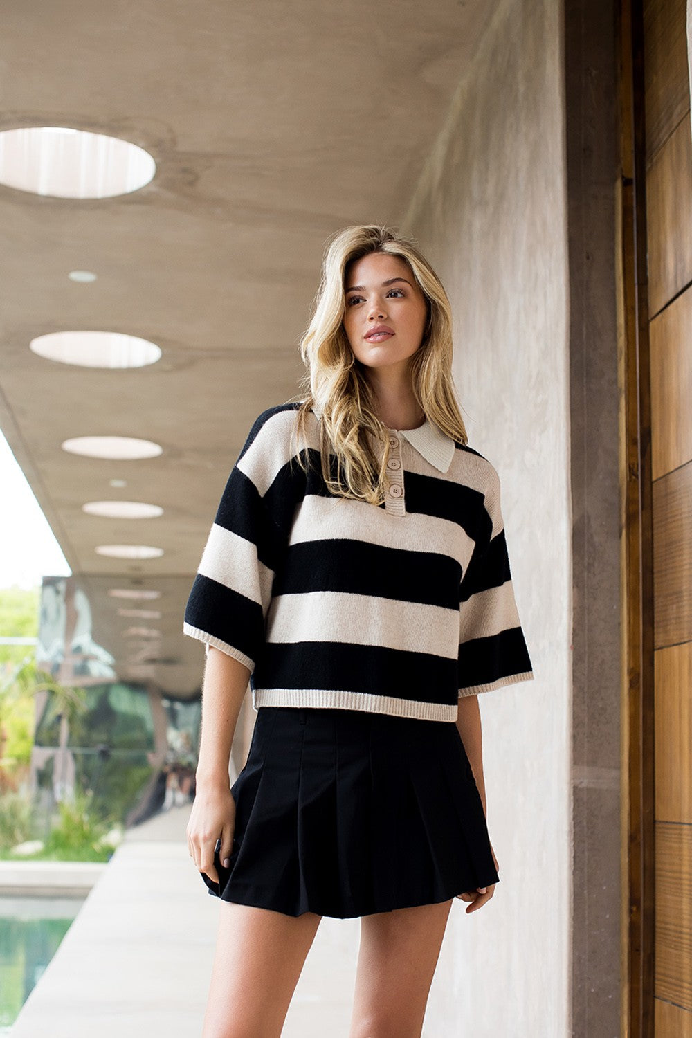 Woman wearing the Angel Striped Half Sleeve Polo Knit Top in black and beige with a black skirt.