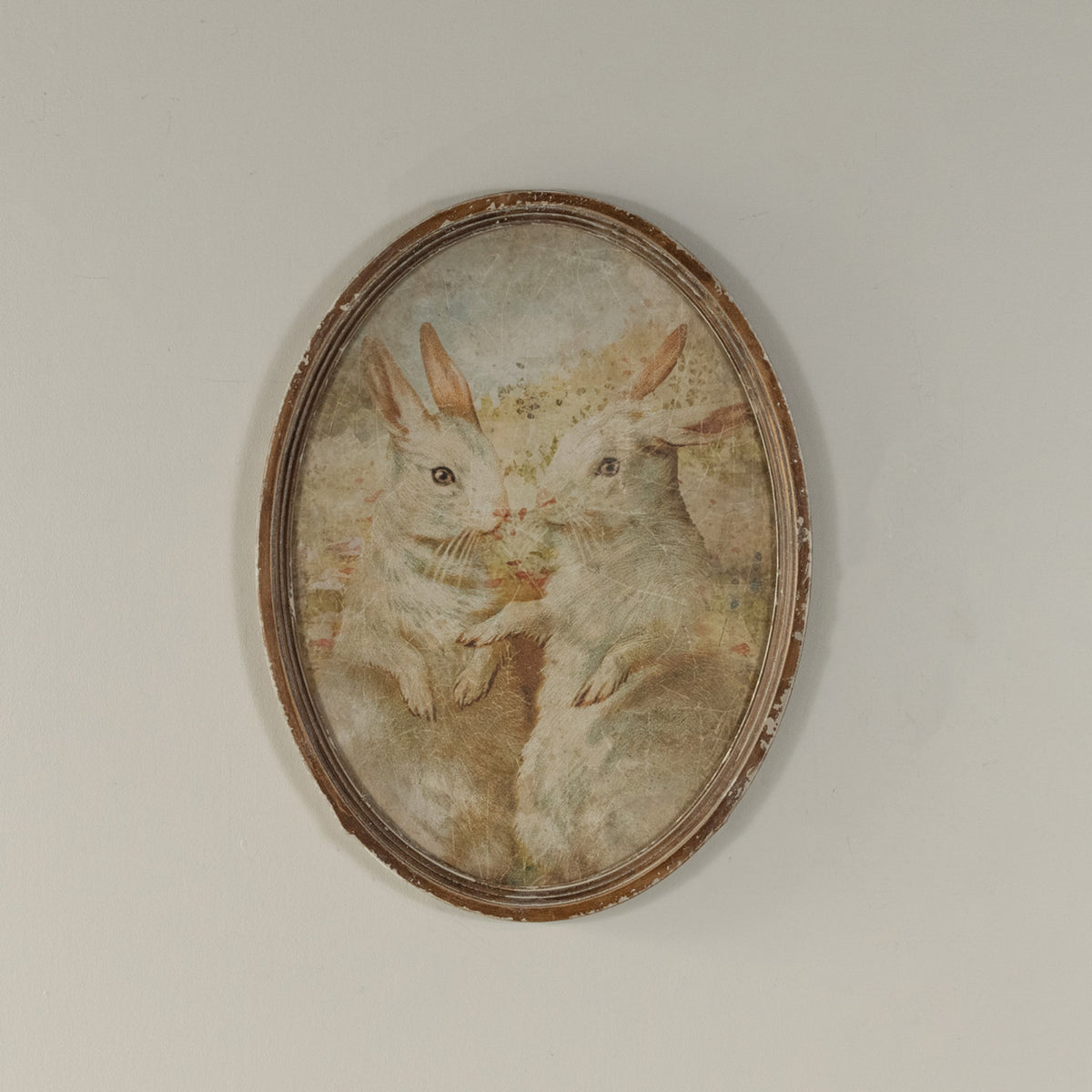 Oval framed duo print featuring two bunny silhouettes on glass over wood.