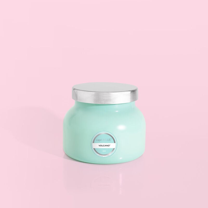 Volcano Aqua Petite Signature Jar 8 oz candle with a silver lid on a pink background.