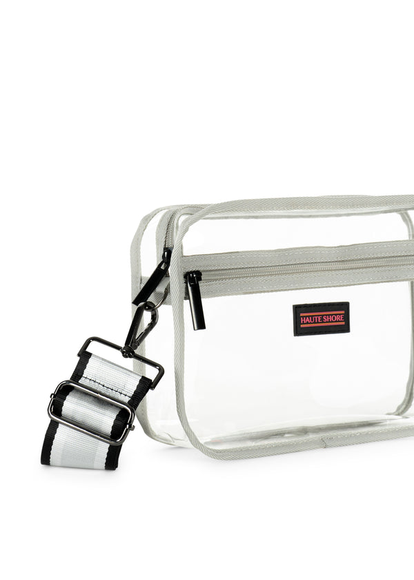 Clear vinyl camera-style crossbody bag with grey trim and a striped black and white strap.