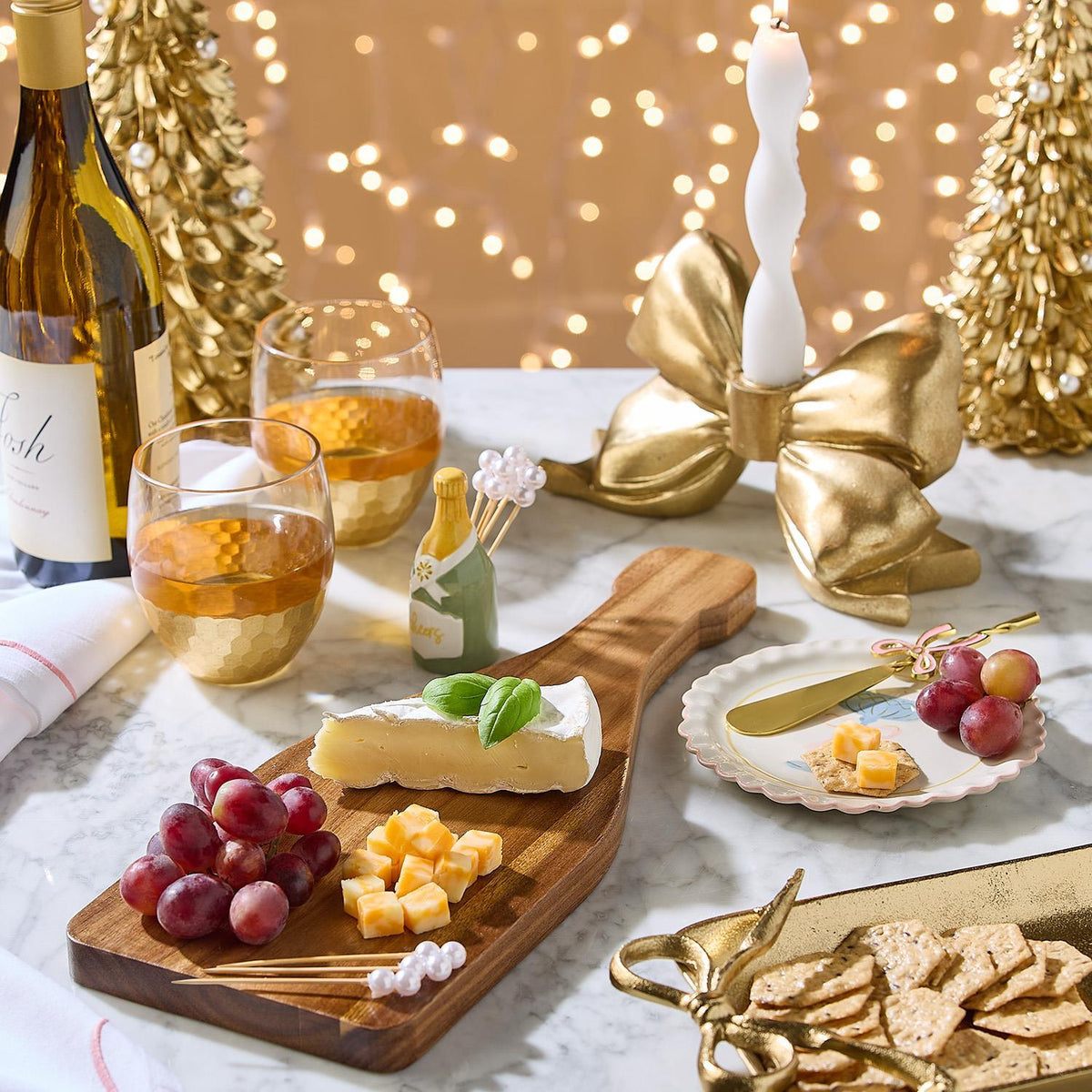 Ceramic champagne bottle pick holder with pearl-topped cocktail picks on a marble table.