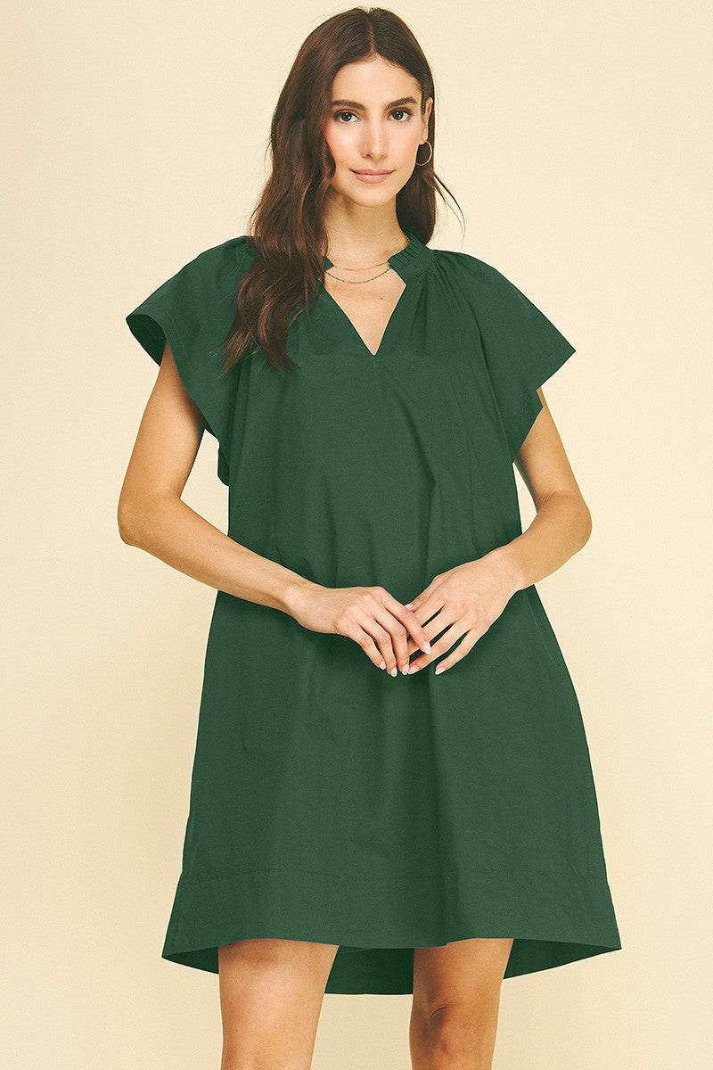 Woman wearing a dark green Amelia Ruffle Detailed Tunic Mini Dress made of 100% cotton.
