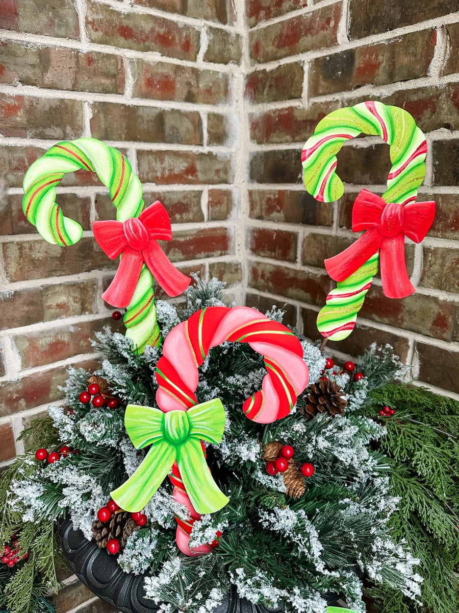 Red candy cane shaped garden stake with white bow accent