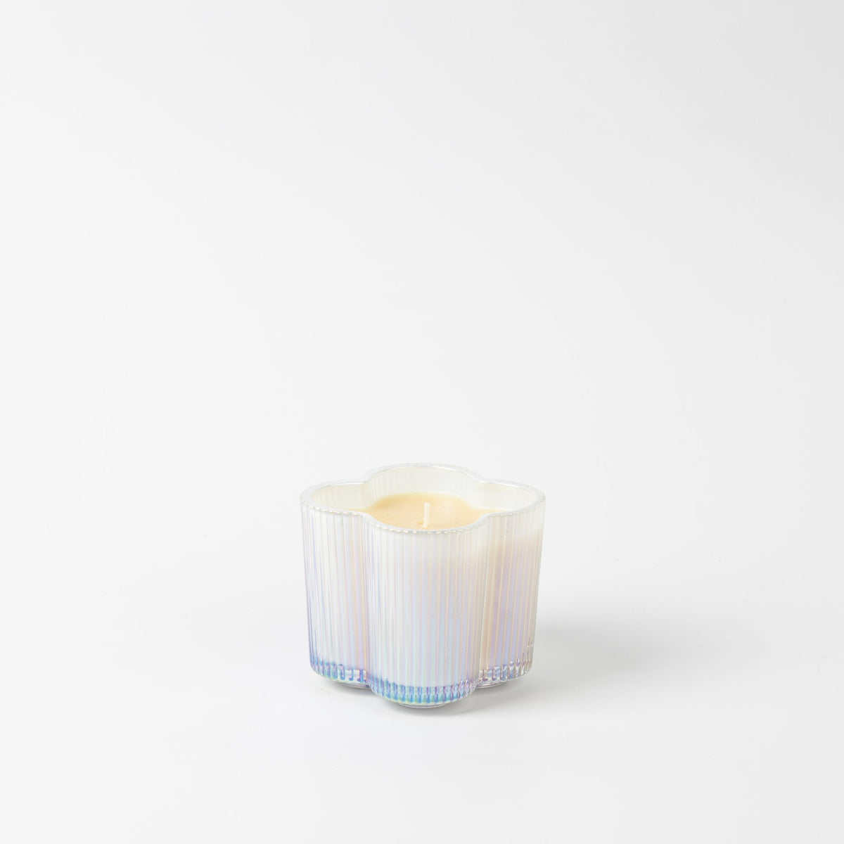 Sweet Grace flower-shaped candle in a ribbed iridescent white glass vessel.
