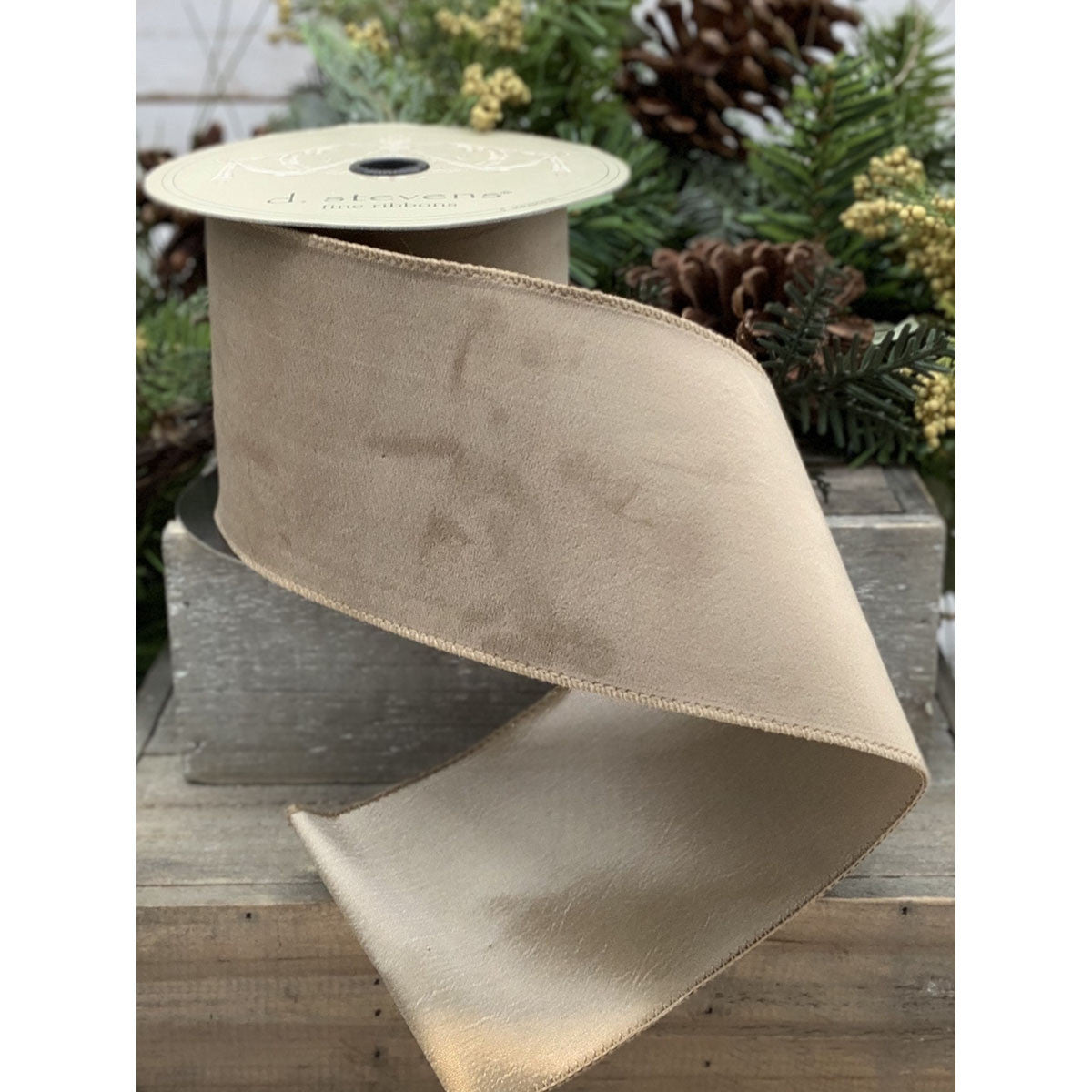 A spool of 2.5-inch wide beige velvet ribbon with a smooth taffeta backing.