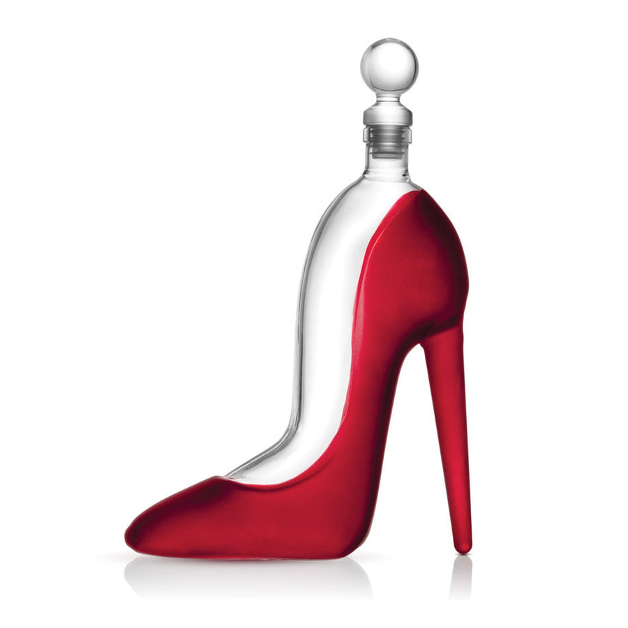 High-heel shaped glass decanter filled with red liquid and a clear glass stopper.