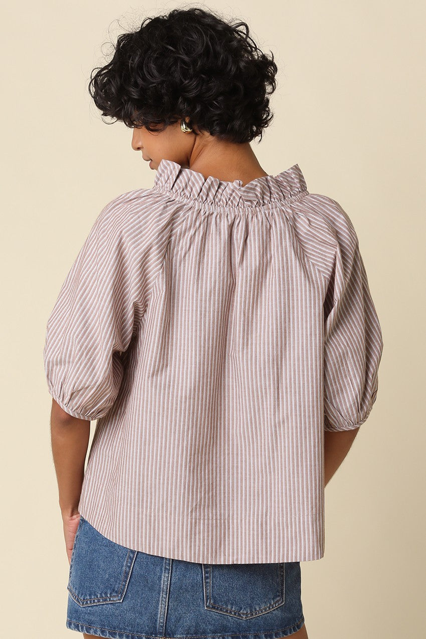 Back view of a woman wearing a mauve and white striped puff sleeve blouse with a ruffled collar.