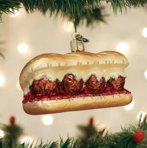 Glass meatball sandwich Christmas ornament with glitter accents hanging on a tree.