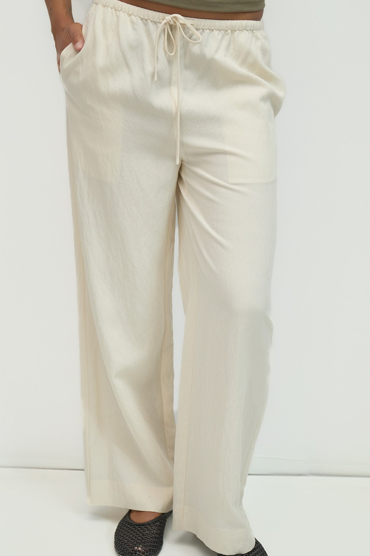 The Jodi Pants in cream, featuring a wide-leg fit, drawstring waist, and front side slit pockets.