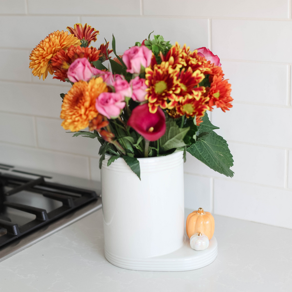 White ceramic Utility Croc with horizontal stripes holding a colorful bouquet of flowers.
