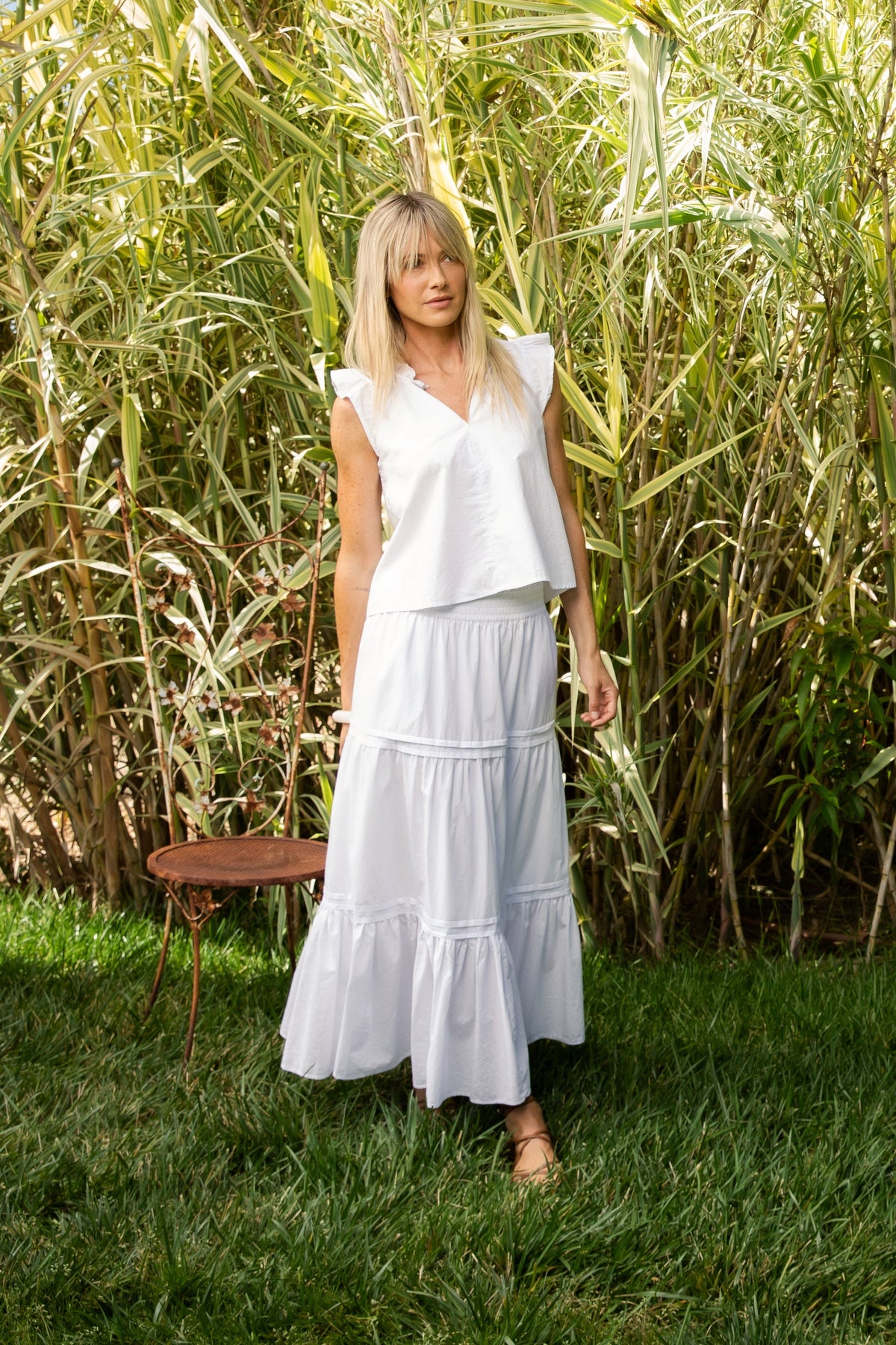 Black poplin sleeveless top with Mandarin collar, V-neckline, ruffle edge, and tie detail.