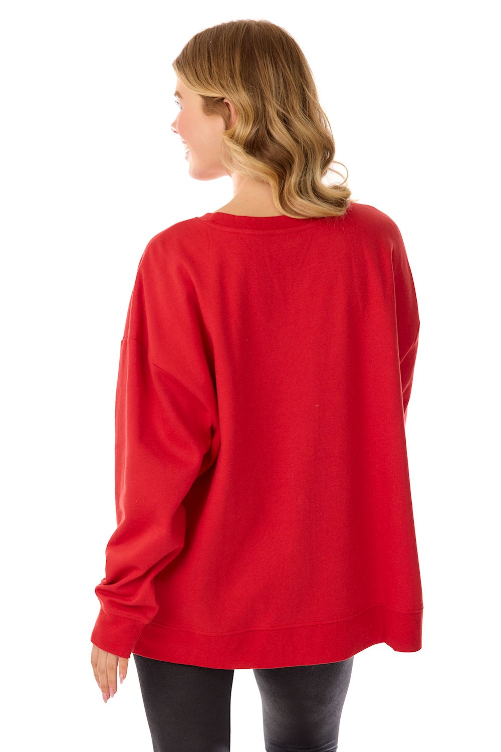 Back view of a woman wearing an oversized red Santa Sparkle Sweatshirt with black leggings.