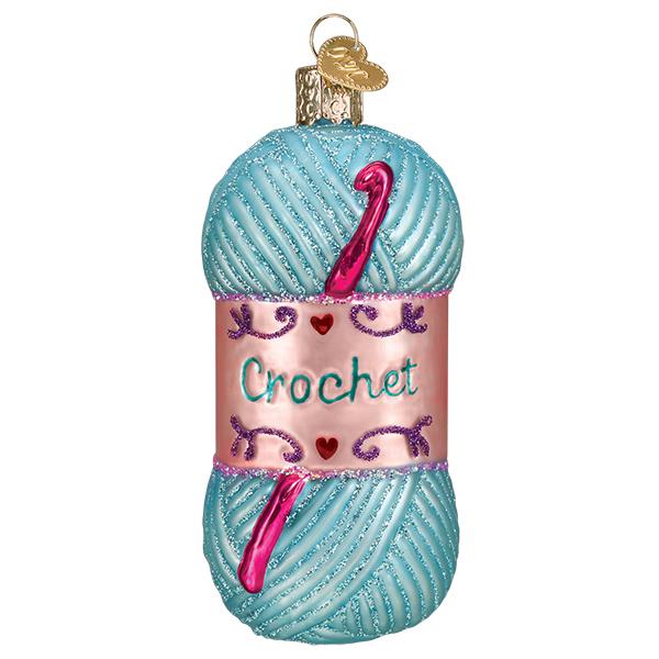 Glass crochet ornament featuring a blue glittery yarn skein with a pink label and crochet hook.