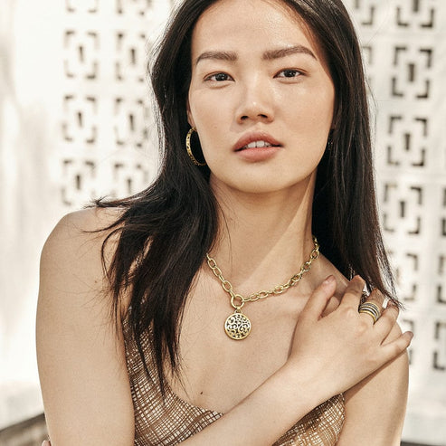 Woman wearing gold-plated Contempo Large Hoop Earrings with intricate scrollwork design.