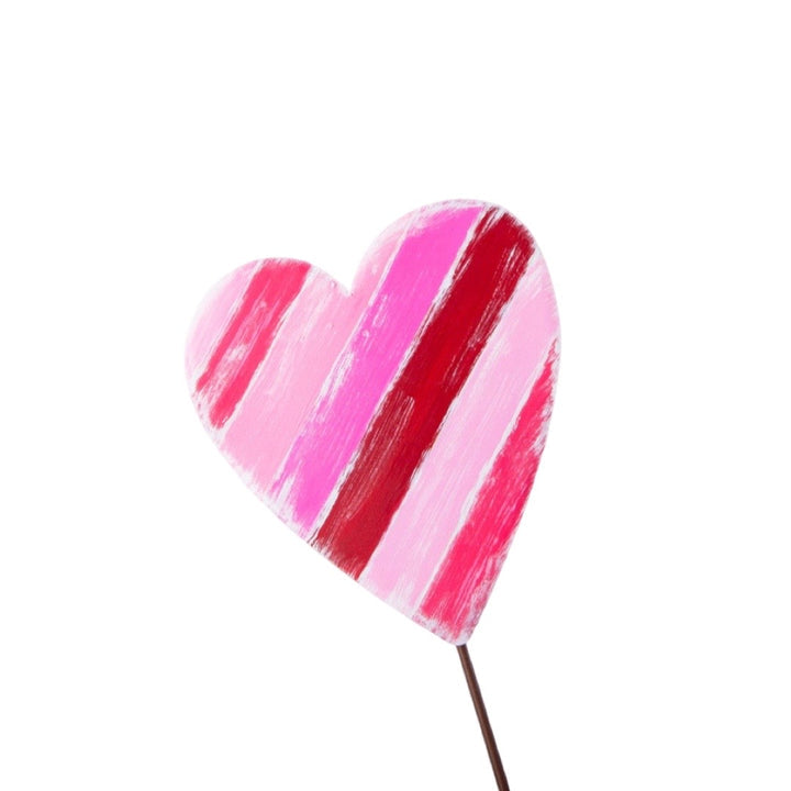 Wooden heart decoration with pink and red diagonal stripes on a stick.