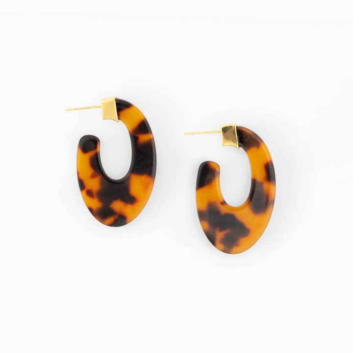 Nellie Tortoise oval hoop earrings with gold-toned brass hardware on a white background.