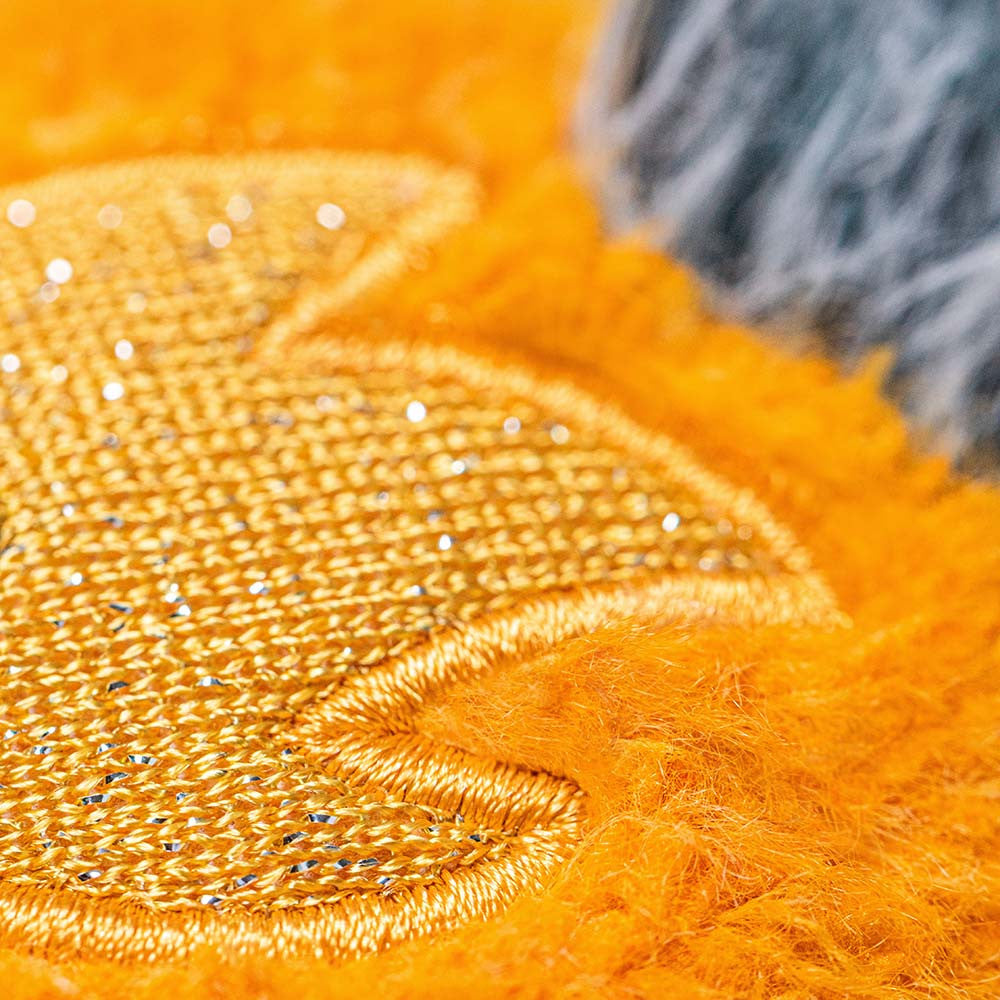 Close-up of the golden embroidered star detail on the orange fuzzy Amuseables Space Comet.