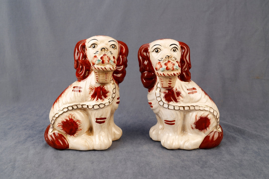 Set of two Staffordshire dog figurines with flower baskets in black ceramic.