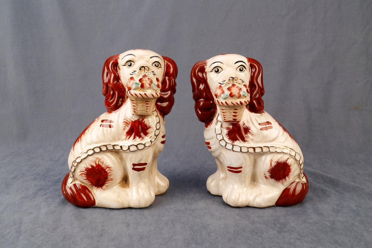 Set of two Staffordshire dog figurines with flower baskets in black ceramic.
