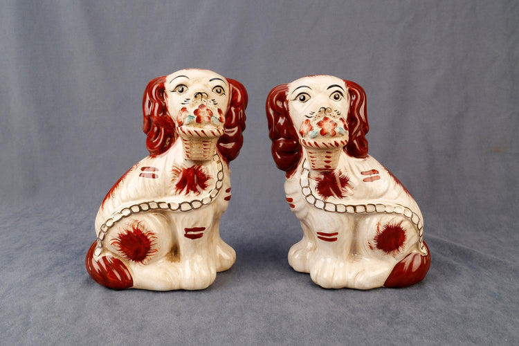 Set of two Staffordshire dog figurines with flower baskets in black ceramic.