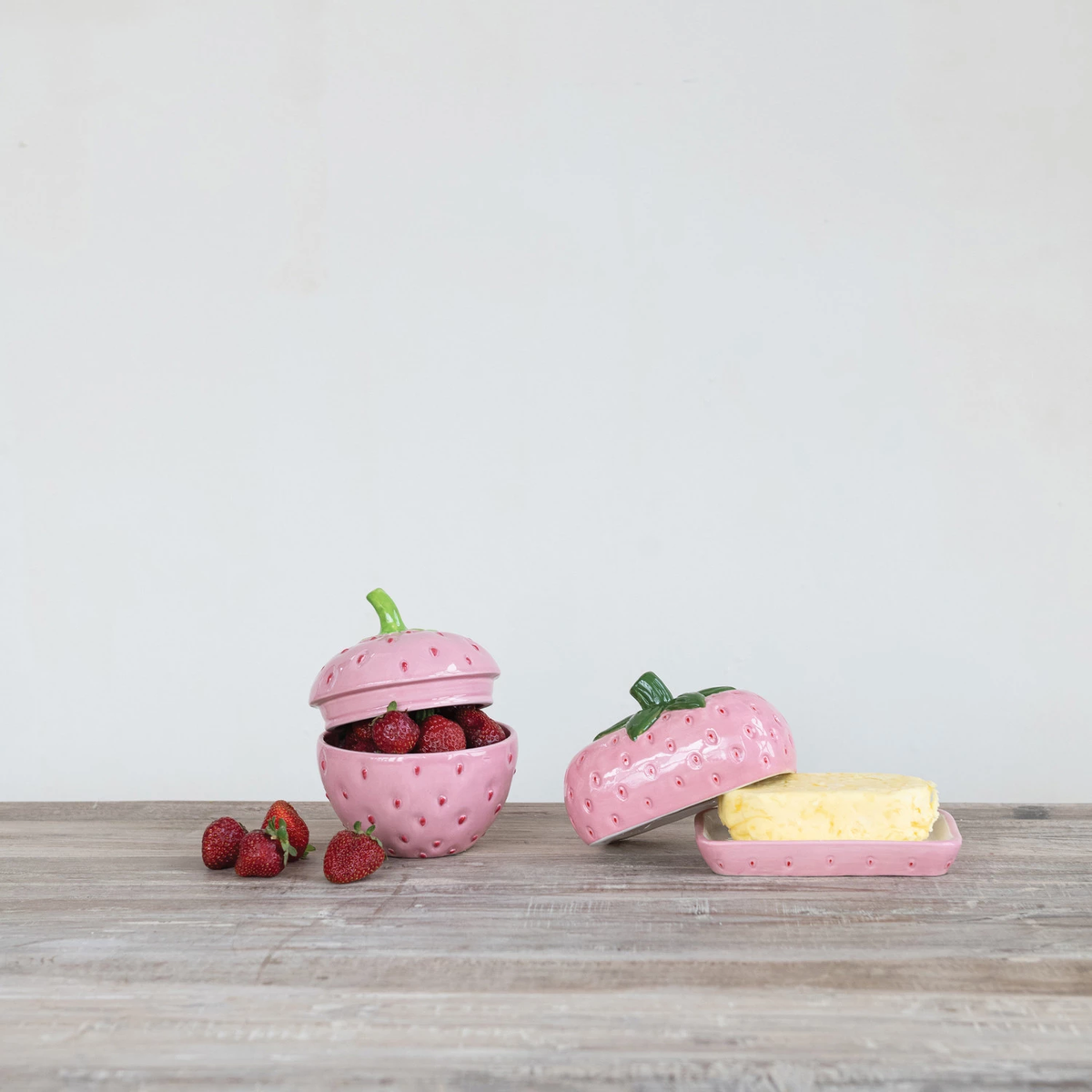 Hand-painted ceramic strawberry-shaped butter dish in red with green leaf stem.