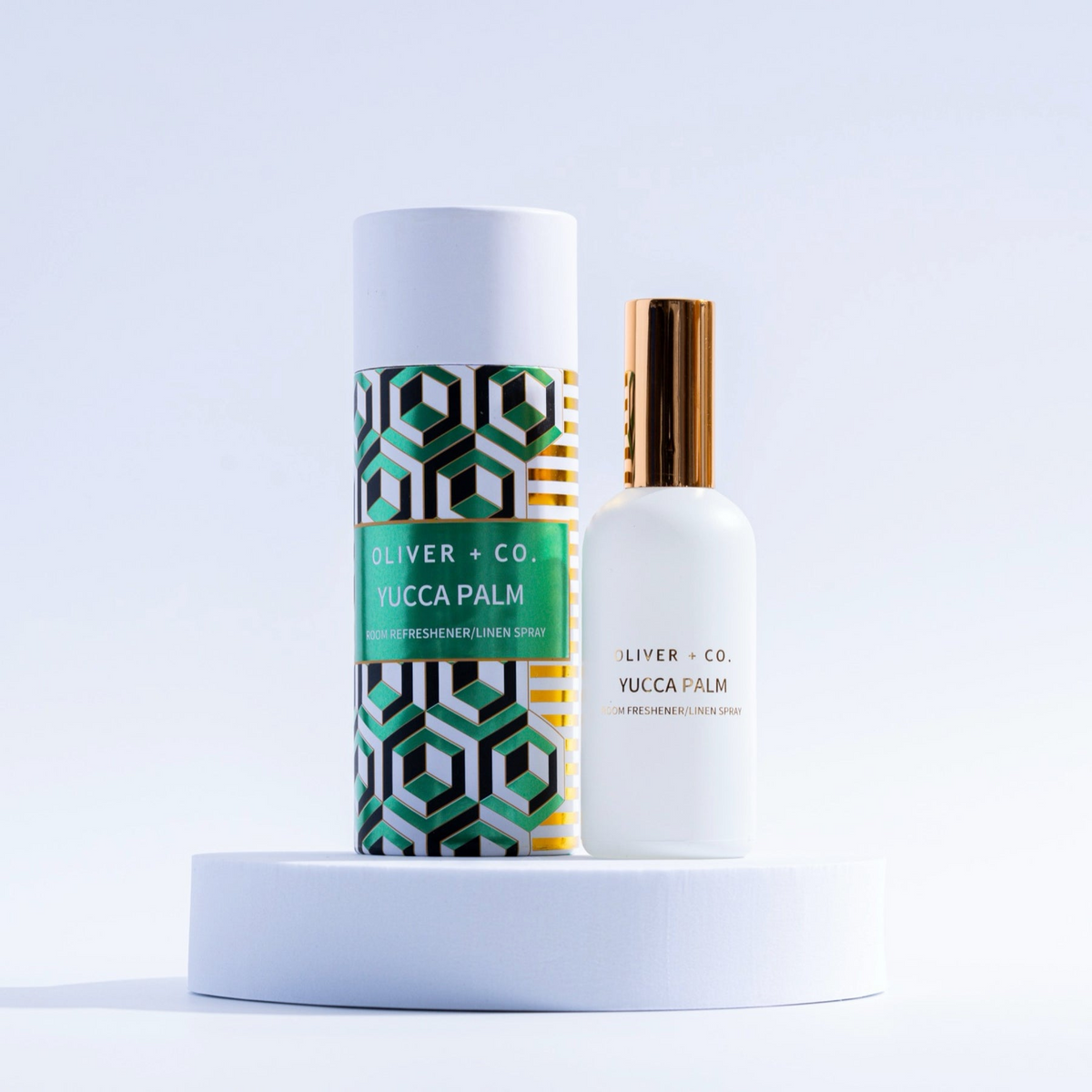 Oliver + Co. Yucca Palm room and linen spray bottle next to its geometric patterned gift tube.