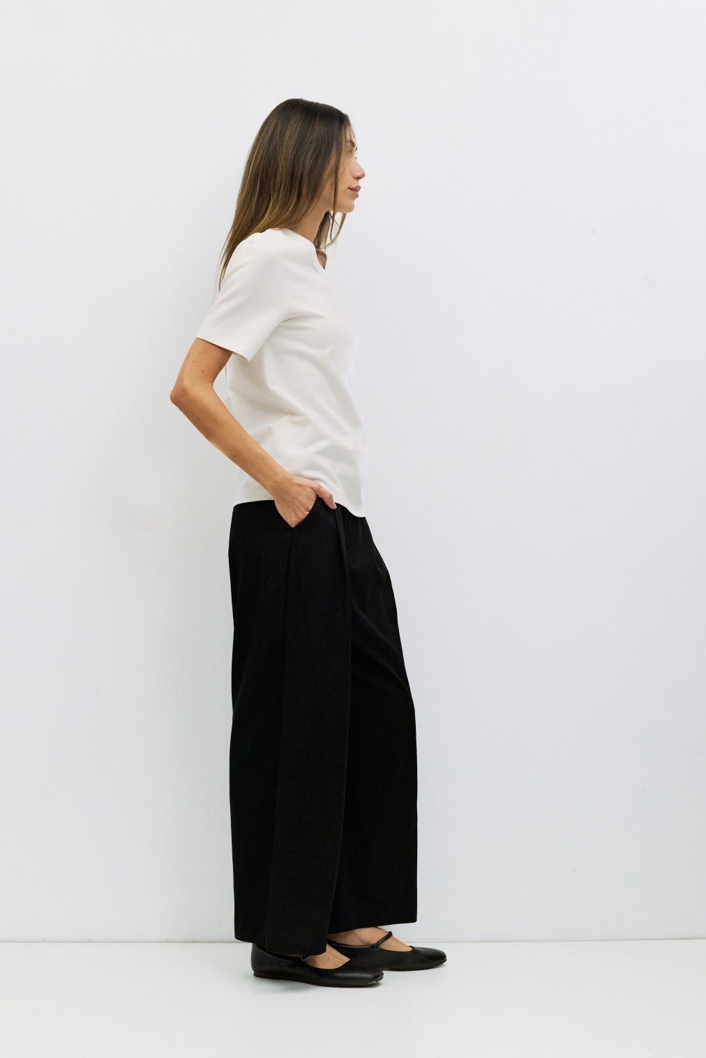 Woman wearing a white short-sleeve Anita Top and black wide-leg pants.