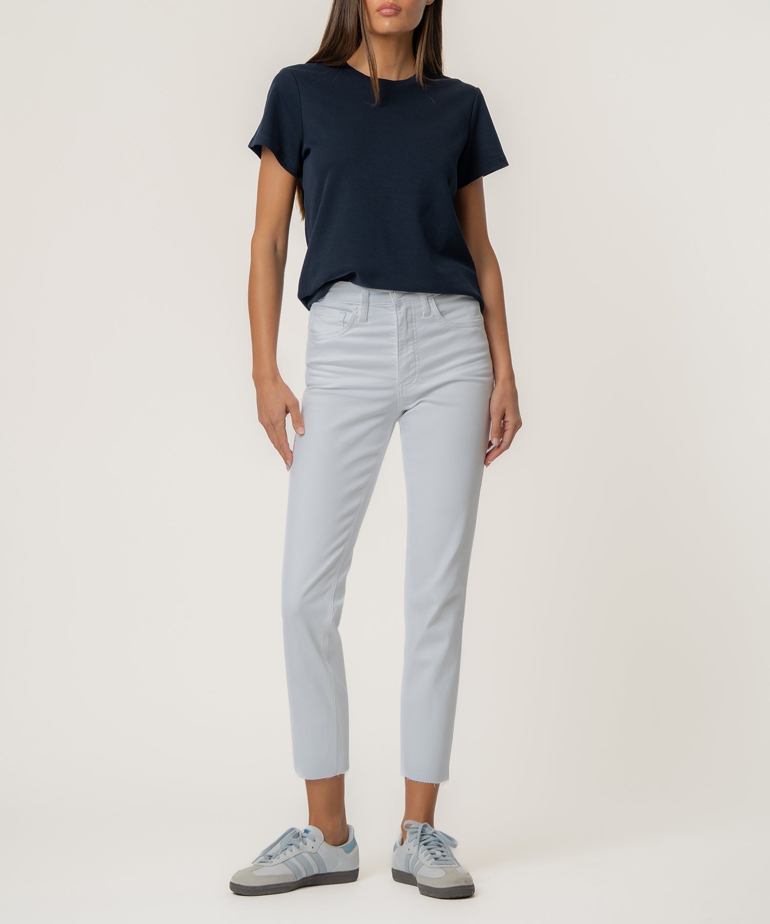 Woman wearing Rachael High Rise Fab Ab Mom jeans in light blue with a raw hem and a navy t-shirt.