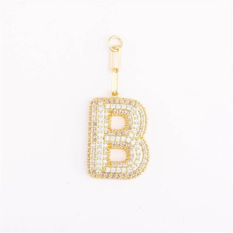 Heather-colored charm bag with pave crystal accents, gold plating, and a customizable initial on an extender chain.