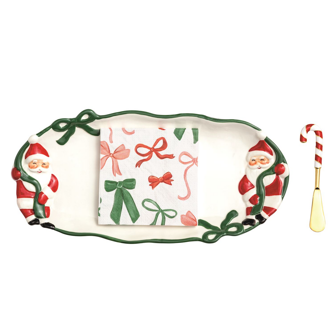 Ceramic Santa tray with green bow rim, candy cane spreader, and bow-patterned cocktail napkins.