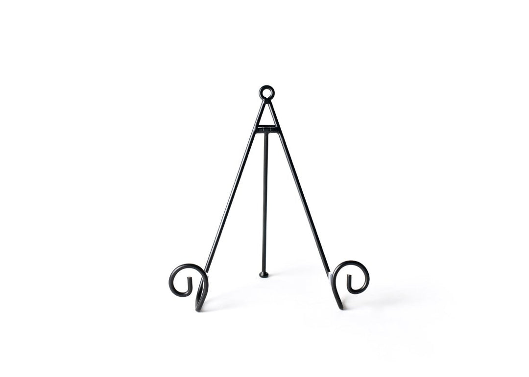 Black metal swirl plate stand with a tripod design and decorative scrolled feet.