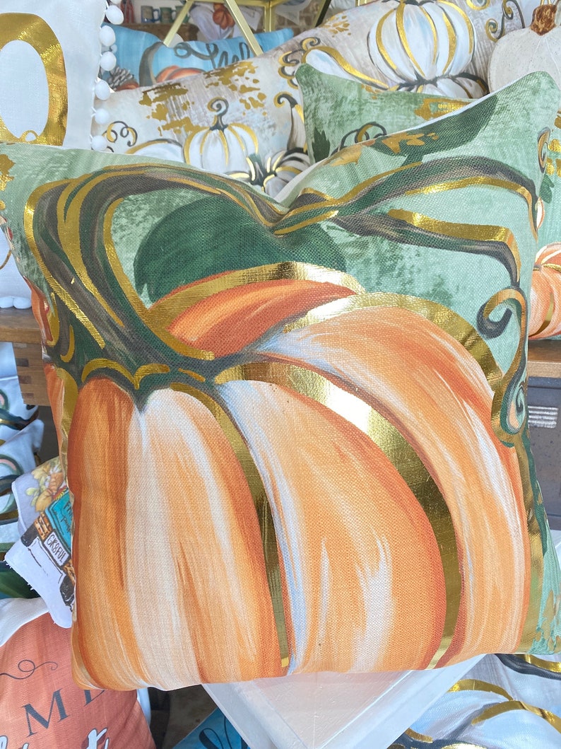 Golden Orange Pumpkin Pillow with metallic gold accents and a green background.