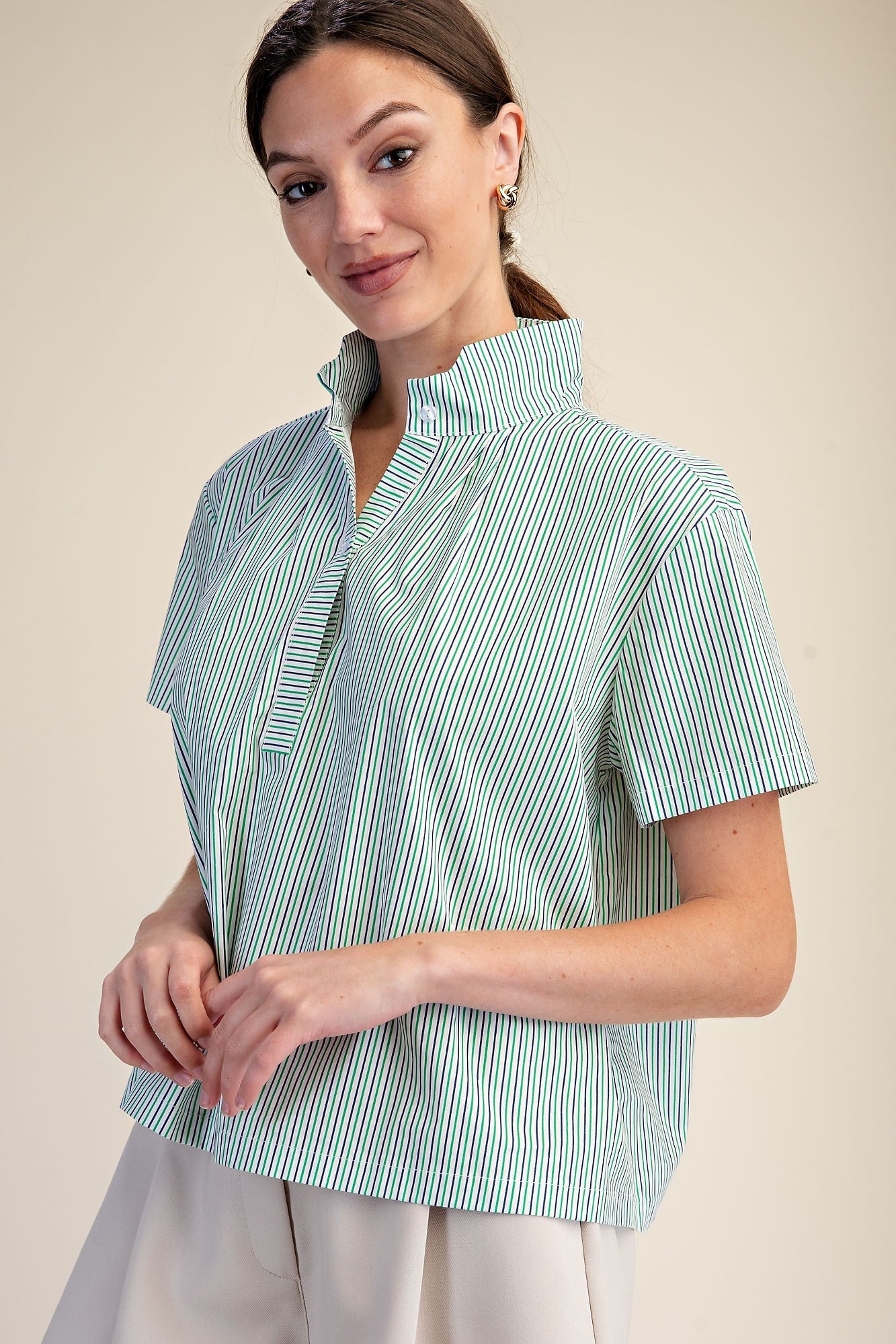 Woman wearing a green and white striped Sarah shirt with a stand collar and short sleeves.