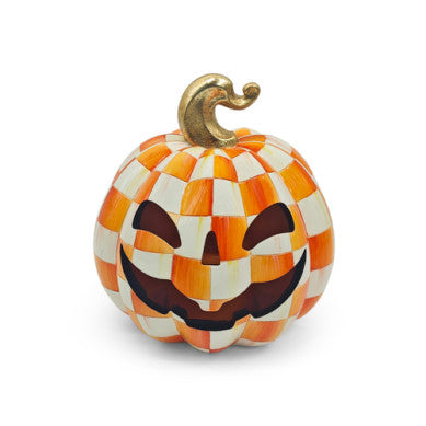 Small orange checkered illuminated jack o'lantern with a glowing face silhouette.
