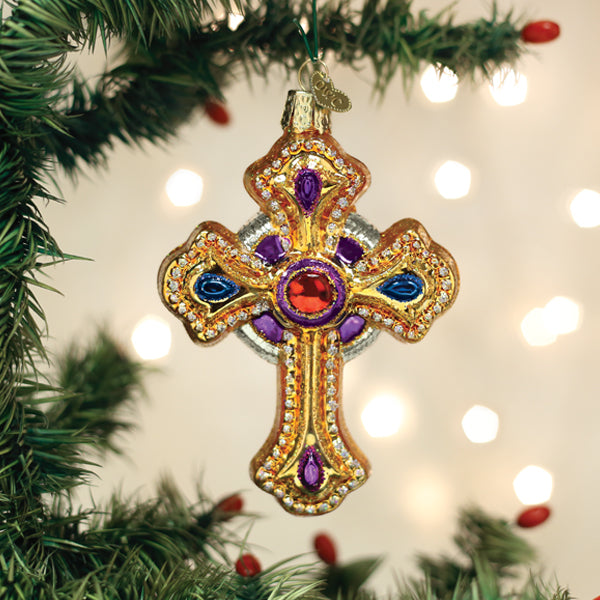Ornate gold cross ornament with purple and blue accents hanging on a Christmas tree.