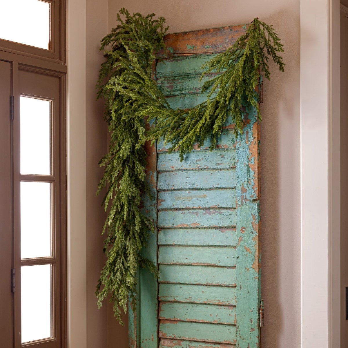 9-foot Native Cedar Garland draped over a rustic turquoise shutter against a neutral wall.