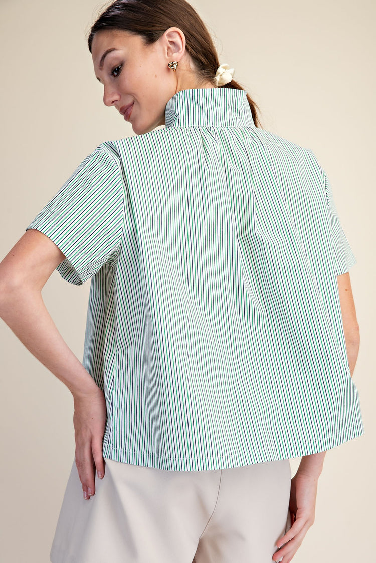 Back view of a woman wearing a green and white striped short sleeve shirt with a stand collar.