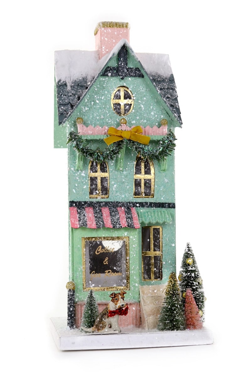 A festive, light green, two-story tea room decoration with snow, garland, and a dog.