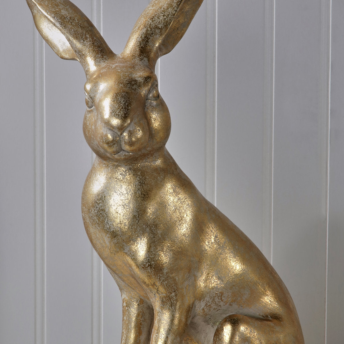 15.5-inch golden resin bunny figurine with a distressed metallic finish against a white wall.