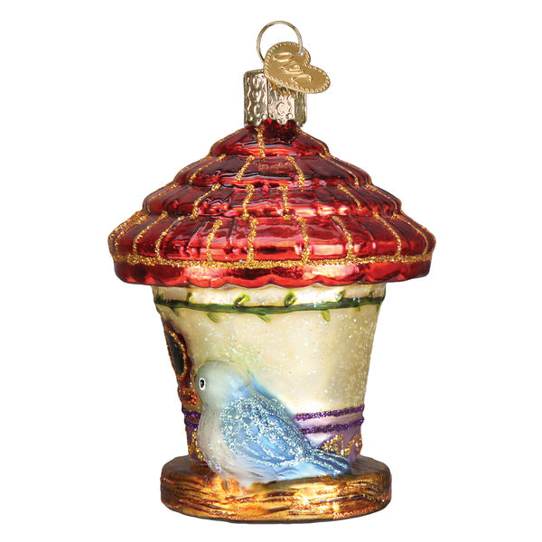 Glass birdhouse ornament with a red glittered roof and a blue bird perched on the side.