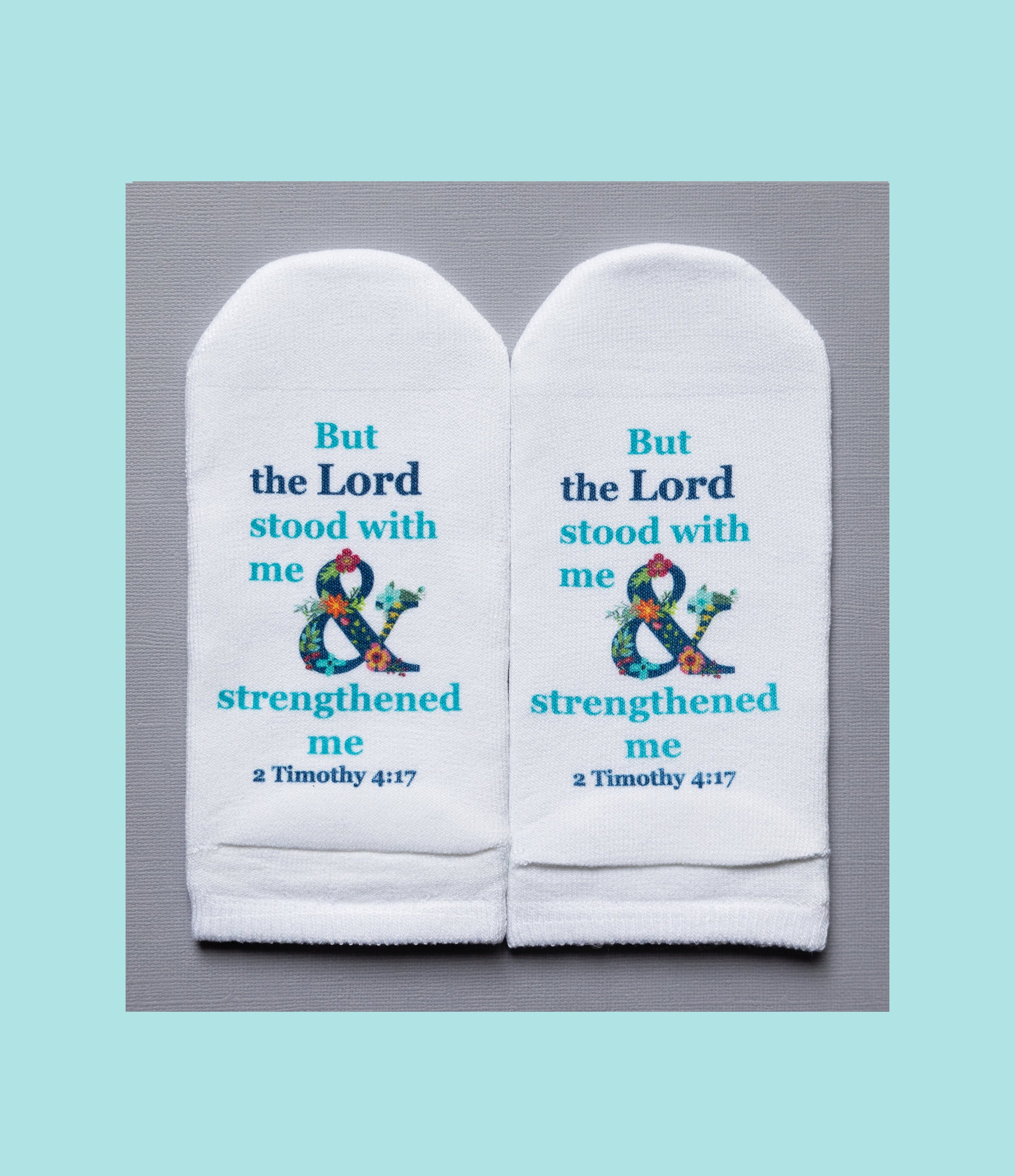 White no-show socks featuring the Bible verse 2 Timothy 4:17 with a floral ampersand design.