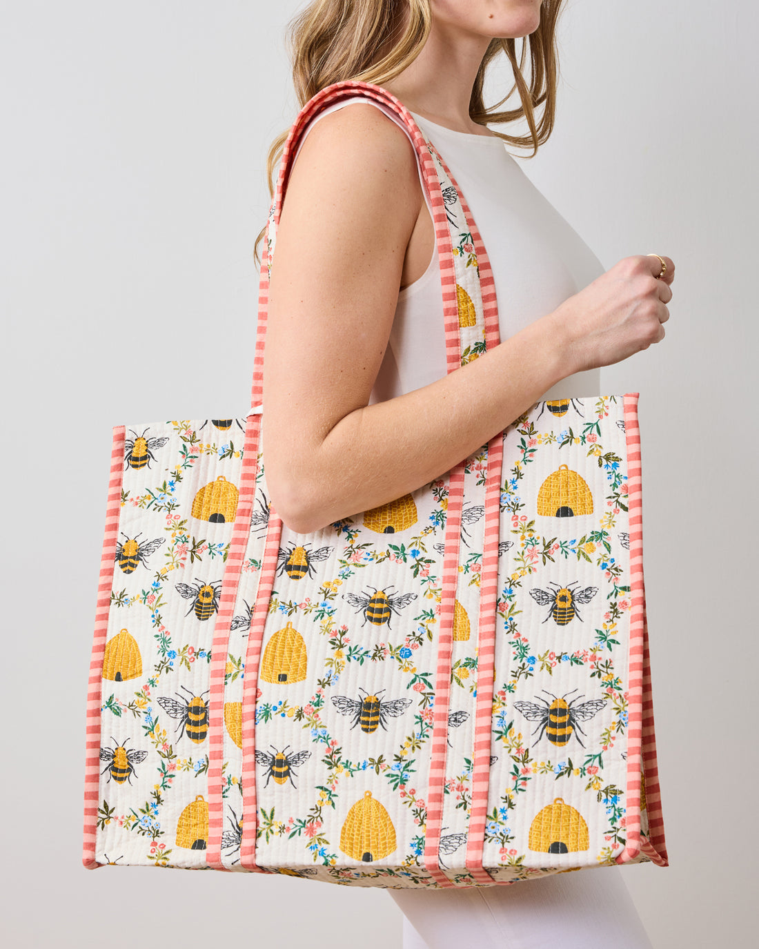 Large quilted organic cotton tote bag in Sweet Bee print with pink striped handles and trim.