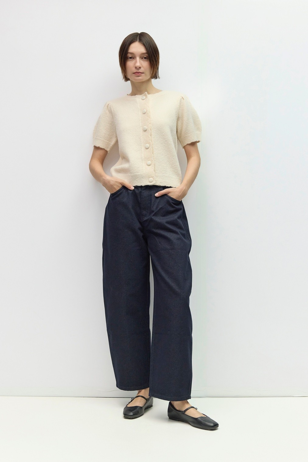 Woman wearing The Mary Kate Top, a cream short puff sleeve knit button-front top with dark denim.