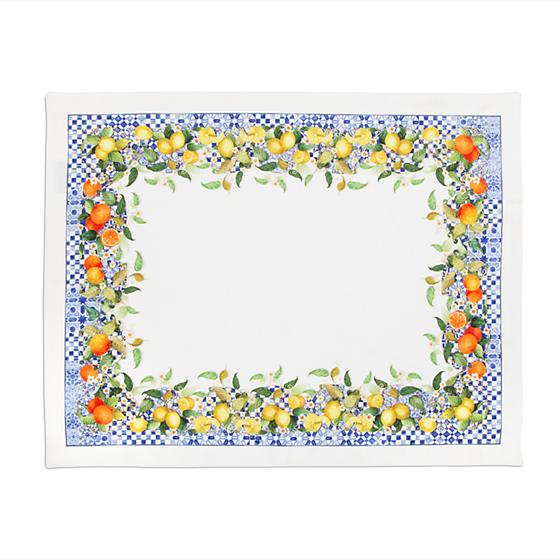 White placemat with a border of blue and ivory checks, lemons, oranges, and green leaves.