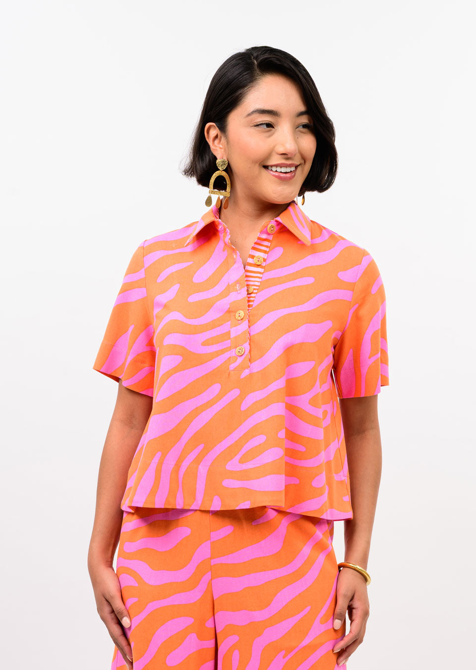 Woman wearing the Agnes Swing Popover Top in an orange and pink zebra print with a pointed collar.