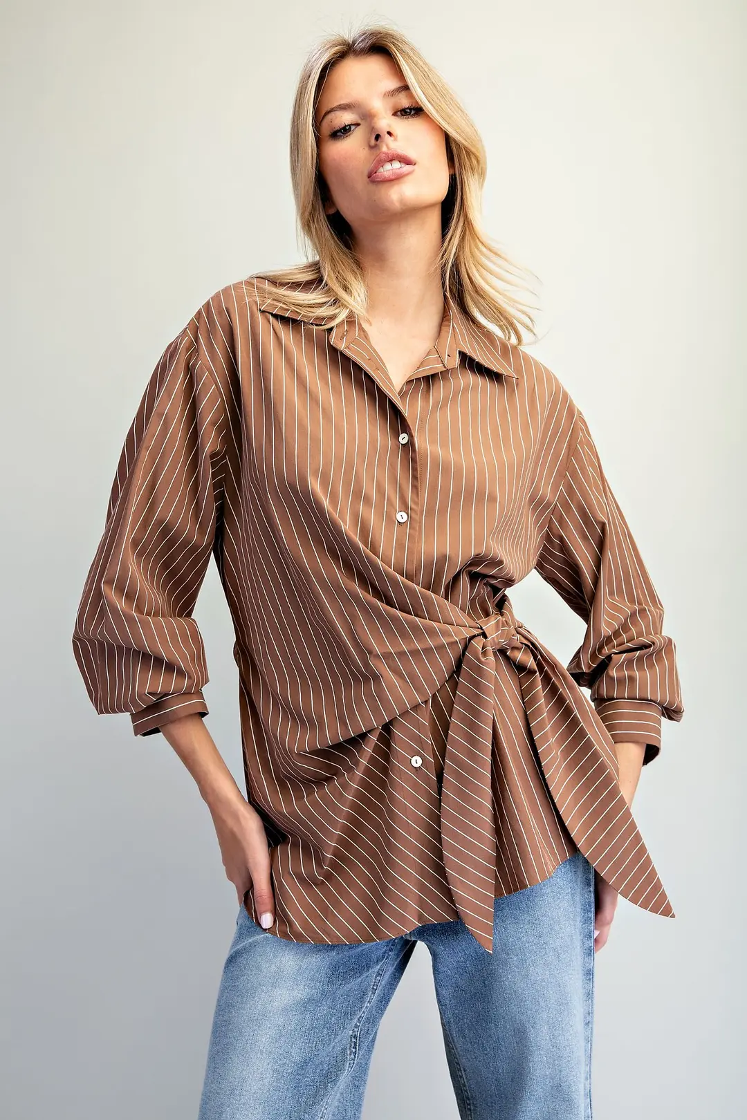 Woman wearing a brown pinstriped Reese Tie Waist Front Blouse with blue jeans.