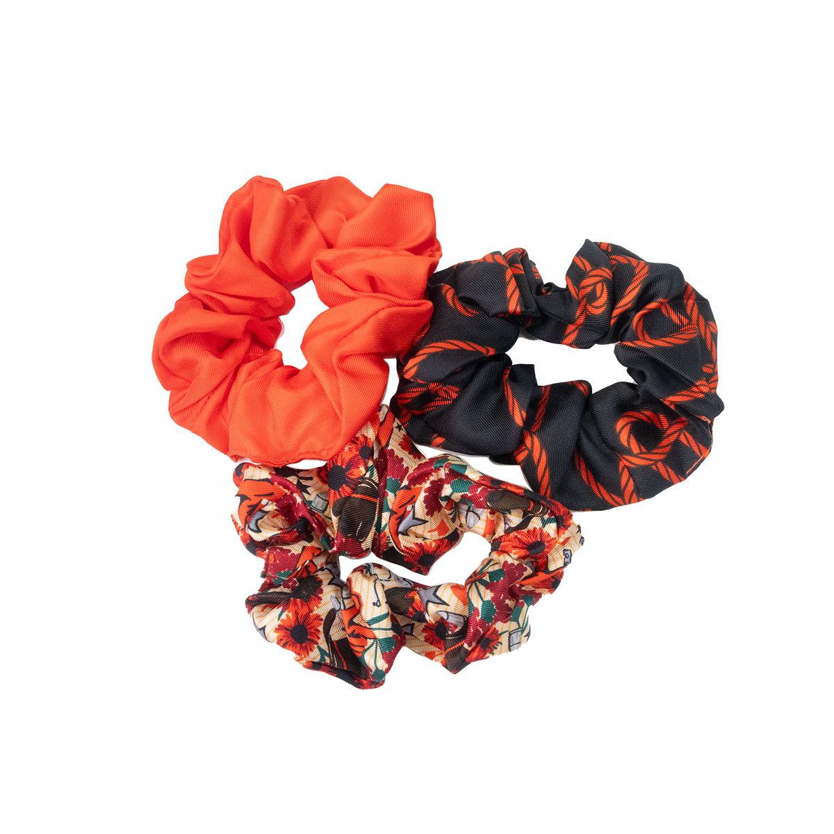 Set of three scrunchies in solid orange, black with orange patterns, and a floral print.